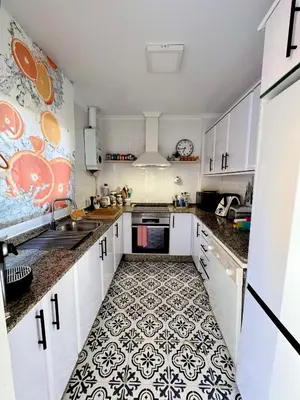 a kitchen with white cabinets and a black and white tile floor at Precioso Adosado El Cormorán Novo Sancti Petri in Novo Sancti Petri