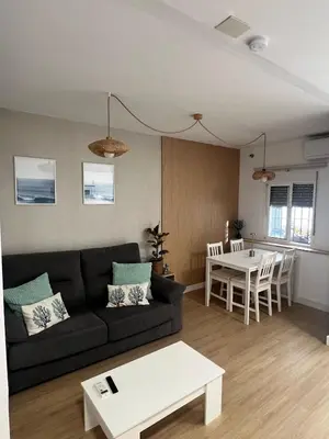 a living room with a black couch and a table at Estudico moderno y cómodo a minutos andando del centro y de la Feria in El Puerto de Santa María