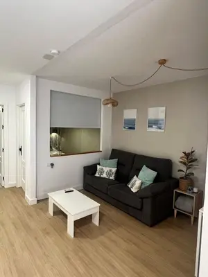 a living room with a black couch and a table at Estudico moderno y cómodo a minutos andando del centro y de la Feria in El Puerto de Santa María