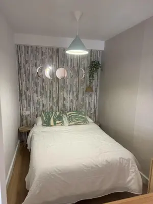 a bedroom with a white bed with green pillows at Estudico moderno y cómodo a minutos andando del centro y de la Feria in El Puerto de Santa María