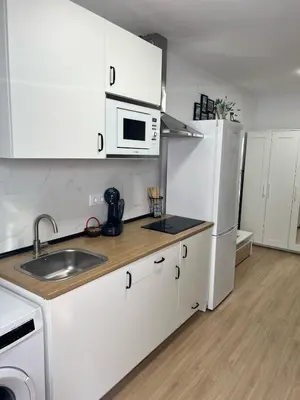 a kitchen with white cabinets and a white refrigerator at Estudico moderno y cómodo a minutos andando del centro y de la Feria in El Puerto de Santa María