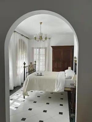 a white bedroom with a bed and a chandelier at Casa rural Pinar de la Plata in Arcos de la Frontera