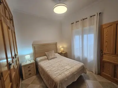 a small bedroom with a bed and a window at El Descanso de Chipiona in Chipiona