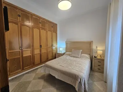 a bedroom with a bed and wooden cabinets at El Descanso de Chipiona in Chipiona
