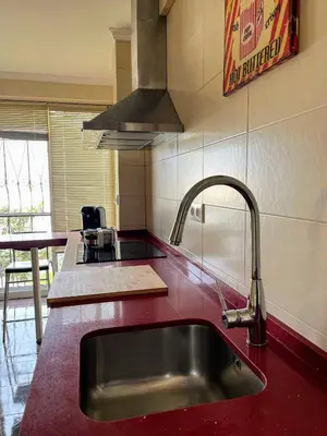 a kitchen with a sink in a red counter top at El Piso in Sanlúcar de Barrameda