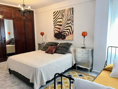 a bedroom with a bed with a painting on the wall at El Piso in Sanlúcar de Barrameda