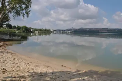 a large body of water with a beach and trees at La Playita de Arcos in Arcos de la Frontera