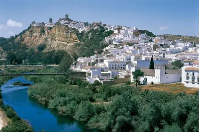 a city with a river in front of a mountain at La Playita de Arcos in Arcos de la Frontera