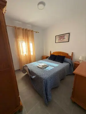 a bedroom with a bed with a blue blanket at El Cotín Rural House in Novo Sancti Petri