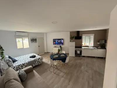 a living room with a couch and a table and a kitchen at Ático Bf Jerez in Jerez de la Frontera