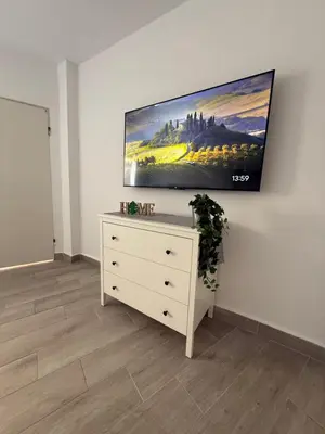 a living room with a dresser with a tv on the wall at Ático Bf Jerez in Jerez de la Frontera