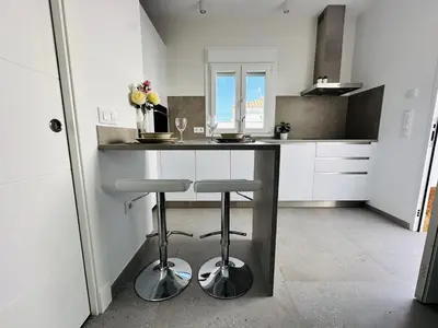 a kitchen with a counter with two stools in it at Pradera Villa Encanto in Chiclana de la Frontera