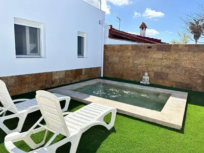 a backyard with two chairs and a swimming pool at Pradera Villa Encanto in Chiclana de la Frontera