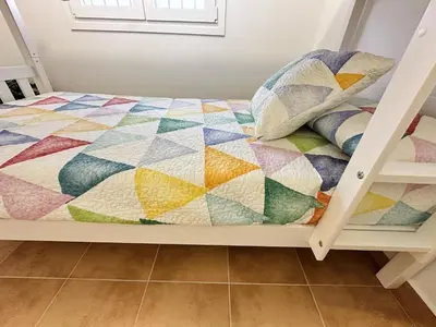 a bed with a colorful quilt on it at Pradera Villa Encanto in Chiclana de la Frontera
