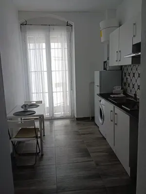 a white kitchen with a table and a stove at Plateros 4 in Jerez de la Frontera