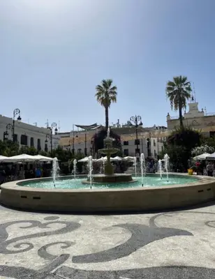 a fountain in the middle of a square with palm trees at Mirador de Sanlucar 3 in Sanlúcar de Barrameda