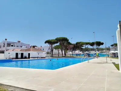a swimming pool with a person riding a bike next to it at Duplex Las Torres La Barrosa - 750m from the Beach in Novo Sancti Petri