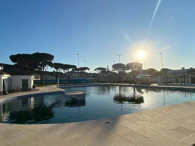 a large swimming pool with the sun in the background at Duplex Las Torres La Barrosa - 750m from the Beach in Novo Sancti Petri