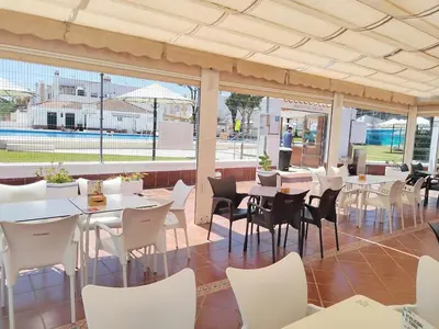 a restaurant with white tables and white chairs at Duplex Las Torres La Barrosa - 750m from the Beach in Novo Sancti Petri