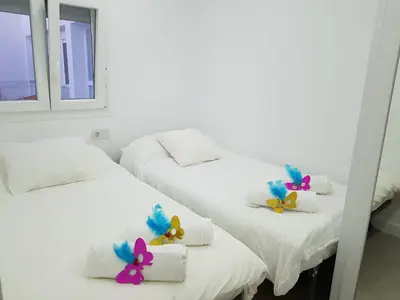 two beds in a room with towels and flowers on them at Playa La Caleta in Cádiz
