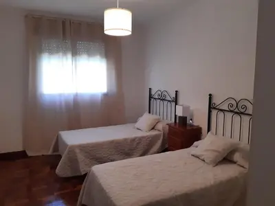 a bedroom with two beds and a window with a light at Casa Toya in Arcos de la Frontera