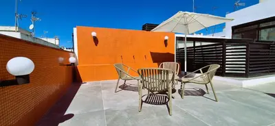 a patio with a table and chairs and an umbrella at Apartamentos Robles 4 by Gades Gestión in Cádiz