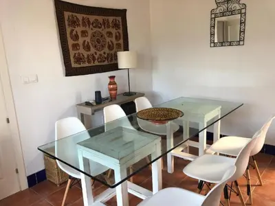 a dining room with a glass table and white chairs at Casa Hortensia in Chiclana de la Frontera