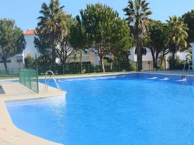 a large blue swimming pool with trees in the background at Casa Hortensia in Chiclana de la Frontera