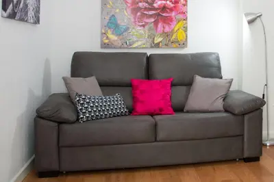 a couch with four pillows on it in a living room at Apartamento Cádiz Centro Histórico in Cádiz