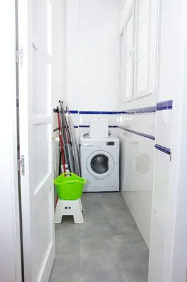 a white bathroom with a washing machine and a green bucket at Apartamento Cádiz Centro Histórico in Cádiz