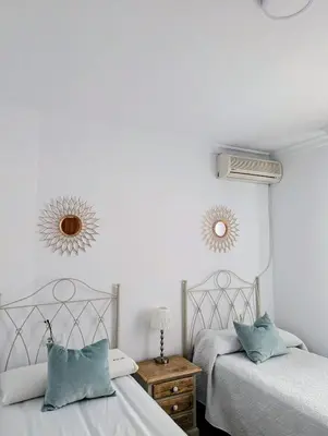 two beds in a bedroom with two mirrors on the wall at Apartamento Plaiya De La Red in Sanlúcar de Barrameda