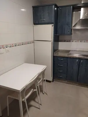 a kitchen with a white table and a white refrigerator at Apartamento Plaiya De La Red in Sanlúcar de Barrameda