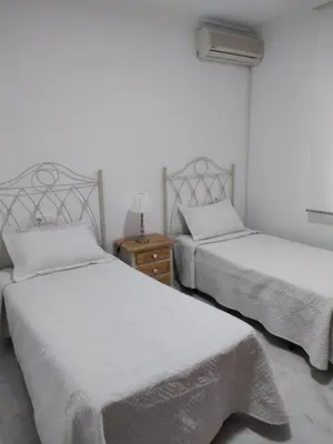 a bedroom with two beds and a nightstand with two beds at Apartamento Plaiya De La Red in Sanlúcar de Barrameda