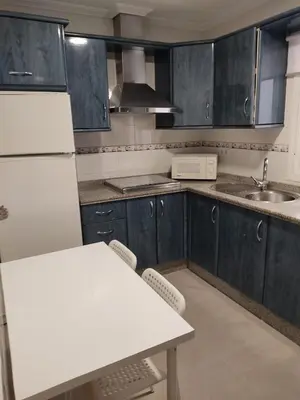 a kitchen with blue cabinets and a table and a sink at Apartamento Plaiya De La Red in Sanlúcar de Barrameda