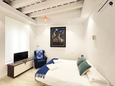 a bedroom with a bed and a tv and a blue chair at Penthouse Libertad Grupo AC Gestion in Cádiz