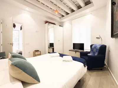a bedroom with a large white bed and a blue chair at Penthouse Libertad Grupo AC Gestion in Cádiz