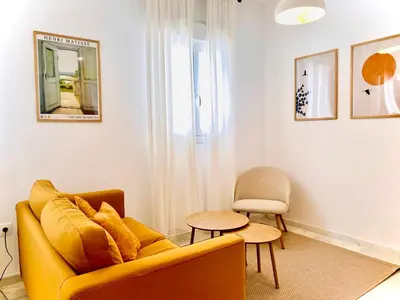 a living room with a yellow couch and a chair at SOL y LETIZIA in Jerez de la Frontera