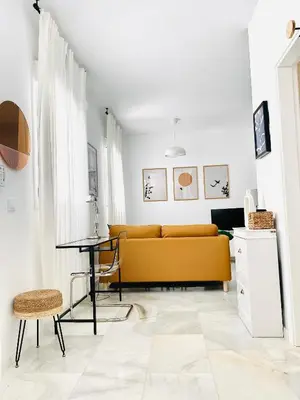 a living room with a yellow couch and a table at SOL y LETIZIA in Jerez de la Frontera