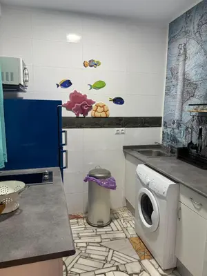 a small white kitchen with a sink and a counter at Apartamento Pacífico in Chipiona