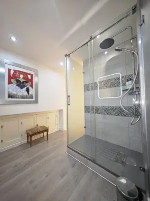 a glass shower in a room with a bench at El Rincón de Ro Little Apartments in Cádiz