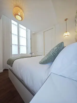 a bedroom with a large white bed with two windows at El Rincón de Ro Little Apartments in Cádiz