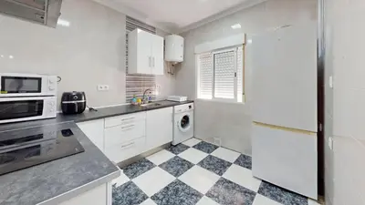 a kitchen with white appliances and a checkered floor at Apartamento Martínez Campos - Playa La Caleta in Cádiz