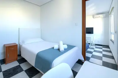 a hotel room with two beds and a tv at Apartamento Martínez Campos - Playa La Caleta in Cádiz