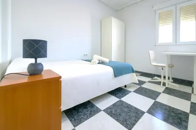 a bedroom with a bed and a checkered floor at Apartamento Martínez Campos - Playa La Caleta in Cádiz