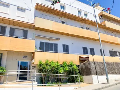 an apartment building with palm trees in front of it at Encantador apartamento in Sanlúcar de Barrameda