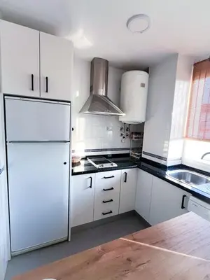 a white kitchen with a sink and a dishwasher at Encantador apartamento in Sanlúcar de Barrameda