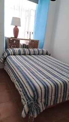 a bed with a striped comforter in a bedroom at Alojamiento Rosalía in Sanlúcar de Barrameda