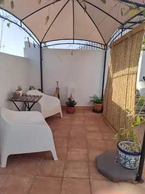 a patio with white furniture and plants in a tent at Alojamiento Rosalía in Sanlúcar de Barrameda