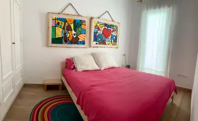 a bedroom with a pink bed with a painting on the wall at nr15 in the heart of Cadiz in Cádiz
