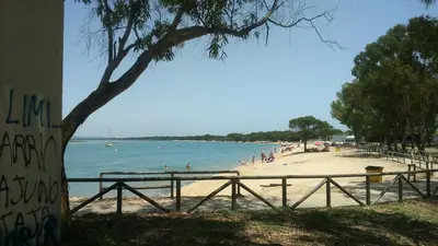 a beach with people in the water and a fence at Apartamento económico verano 3 DORMITORIOS in El Trocadero